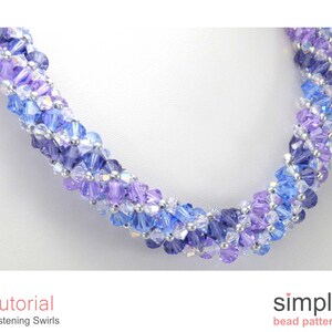 May include: A close-up of a blue and purple beaded necklace with a silver accent. The necklace is made with small, faceted beads and has a swirling pattern. The necklace is on a white background.