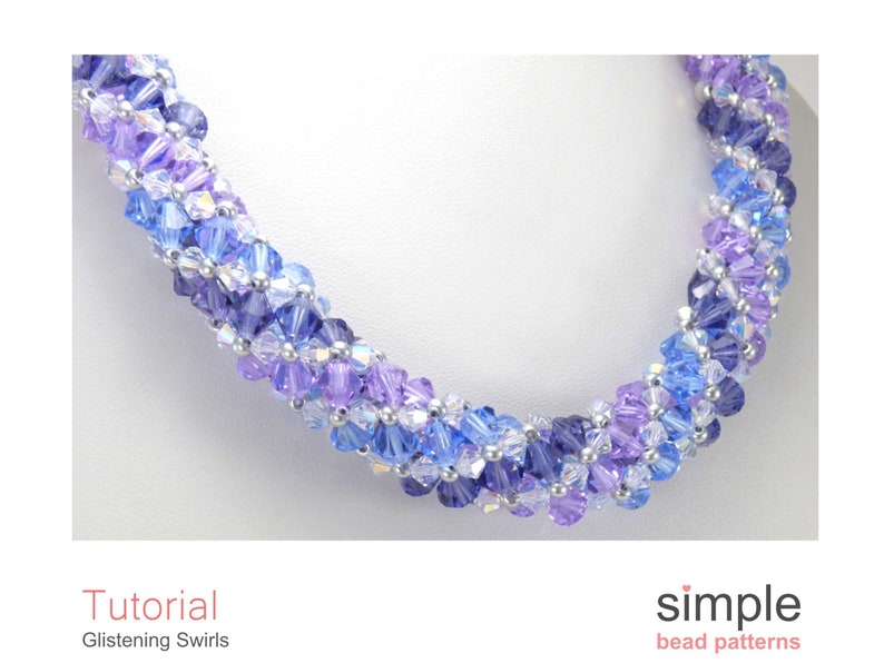 May include: A close-up of a blue and purple beaded necklace with a silver accent. The necklace is made with small, faceted beads and has a swirling pattern. The necklace is on a white background.