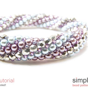 Pode incluir: Um close-up de um bracelete de contas com um design torcido. O bracelete é feito com contas prateadas, azul claro e roxas.