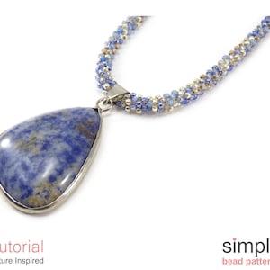 Könnte beinhalten: Eine blaue und silberne Perlenkette mit einem großen blauen Edelstein-Anhänger. Die Kette ist aus kleinen Perlen gefertigt und hat ein schlichtes Design. Der Anhänger hat eine Tropfenform und eine silberne Fassung.