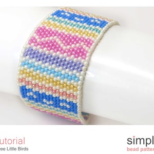 May include: A colourful beaded bracelet with a striped pattern in shades of pink, blue, yellow, and white. The bracelet is made with small seed beads and has a simple design.