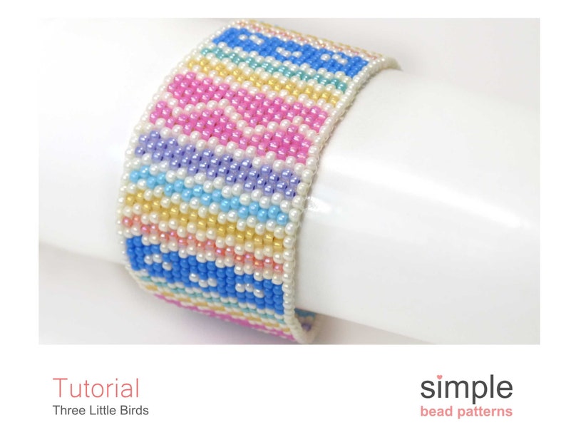 May include: A colourful beaded bracelet with a striped pattern in shades of pink, blue, yellow, and white. The bracelet is made with small seed beads and has a simple design.