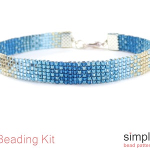 May include: A beaded bracelet with a blue and tan pattern. The bracelet is made of small, square beads and has a silver clasp. The words "Beading Kit" are in red text at the bottom of the image.