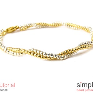 以下が含まれることがあります： ねじれたデザインのゴールドとシルバーのビーズブレスレット。ブレスレットは小さく丸いビーズで作られており、シンプルな留め具が付いています。