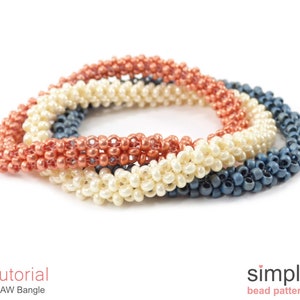 Könnte beinhalten: Drei Perlenarmbänder in Koralle, Weiß und Marineblau. Die Armbänder sind aus kleinen Rocailles gefertigt und übereinander gestapelt. Die Armbänder werden als "CRAW Bangle" bezeichnet und sind ein Tutorial von "simple bead patterns".