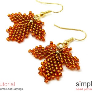 May include: A pair of gold beaded earrings shaped like autumn leaves. The leaves are made with small, orange-brown beads and are attached to gold ear wires.