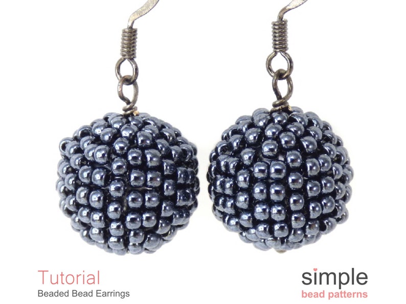 May include: A pair of beaded earrings in a dark grey, almost black, colour. The earrings are made of small beads clustered together to form a sphere shape. The earrings are attached to silver-toned ear wires.