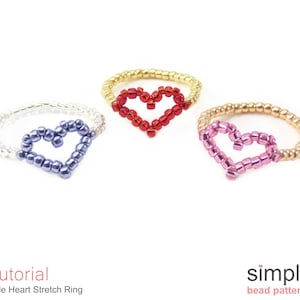 May include: Three beaded stretch rings with heart shapes. The rings are in red, purple, and pink.