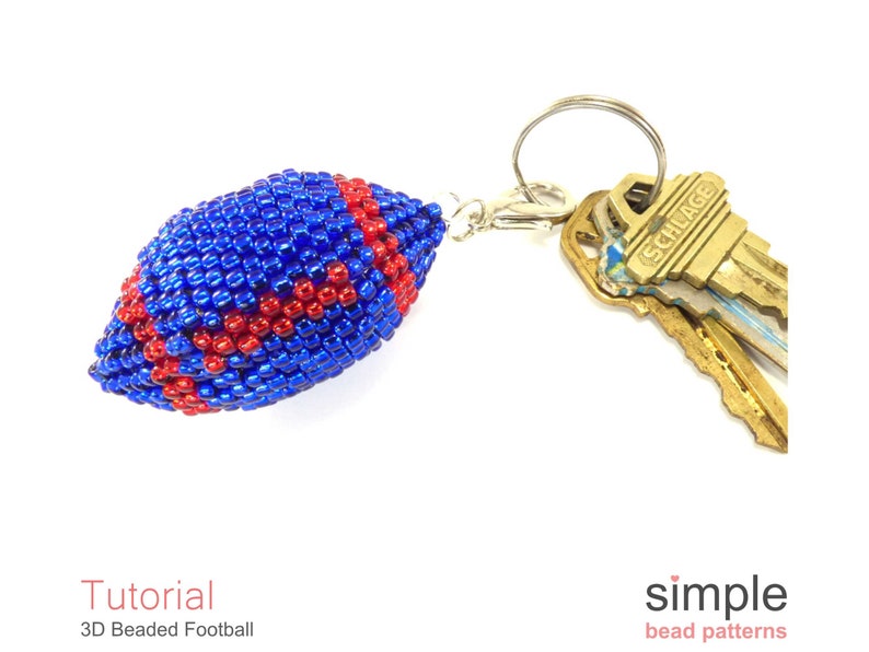 May include: A blue and red beaded football keychain. The football is attached to a silver key ring with a silver clasp. The keychain is hanging from a set of keys.