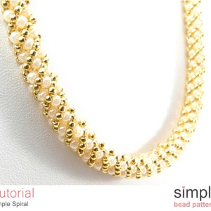 Peut inclure: Un collier en perles dorées et blanches. Le collier est composé de petites perles rondes et présente un motif en spirale simple. Le collier est sur un fond blanc.