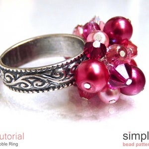 Może przedstawiać: Srebrny pierścionek z ozdobnym wzorem i gromadą r&oacute;żowych i czerwonych koralik&oacute;w. Korale są połączeniem kształt&oacute;w okrągłych i fasetowanych.