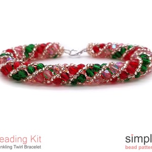 May include: A red, green, and gold beaded bracelet with a silver clasp. The bracelet is made with small, faceted beads and has a twirling design. The bracelet is labeled "Twinkling Twirl Bracelet" and is part of a beading kit.