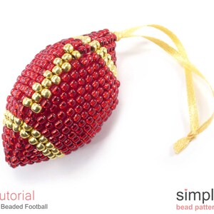 May include: A red and gold beaded football ornament with a gold ribbon for hanging. The ornament is a 3D beaded design and is a tutorial for a 3D beaded football.