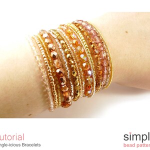 Pu&ograve; includere: Un set di braccialetti di perline dorate e ambrate sul polso di una persona. I braccialetti sono realizzati con perline di diverse dimensioni e forme, creando un aspetto stratificato e testurizzato.