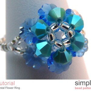 May include: A blue crystal flower ring with silver beads. The ring is made with small, faceted crystals and is a delicate piece of jewelry.