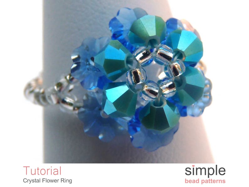 May include: A blue crystal flower ring with silver beads. The ring is made with small, faceted crystals and is a delicate piece of jewelry.