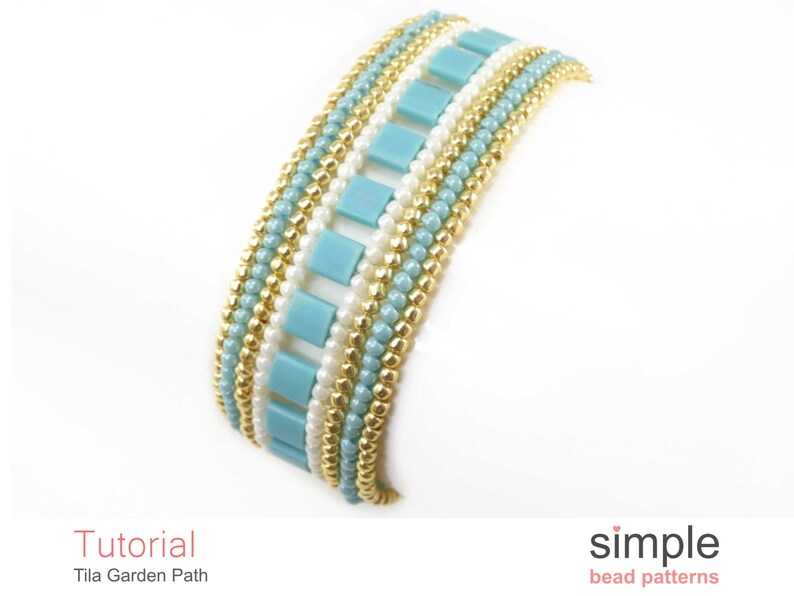 May include: A beaded bracelet featuring a pattern of gold, white and light blue beads. The bracelet is crafted with small, round beads and larger, square beads. The bracelet is called "Tila Garden Path" and is a "simple bead pattern".