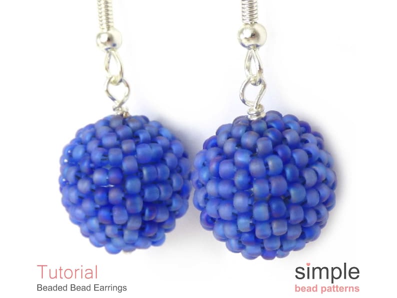 May include: A pair of blue beaded earrings with silver ear wires. The beads are small and round, creating a spherical shape. The earrings are a simple and elegant design.