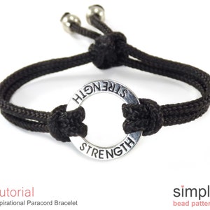 May include: Black paracord bracelet with a silver metal ring that says "STRENGTH" on it.