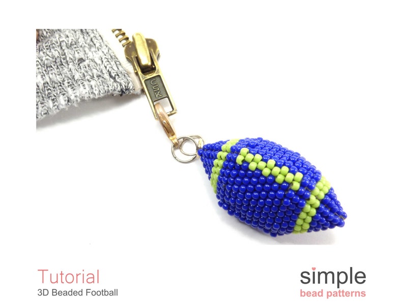 May include: A blue and green beaded football charm with a gold zipper pull attached. The charm is a 3D beaded design and is a great addition to a bag or keychain.