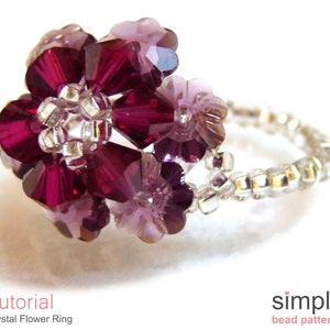 May include: A crystal flower ring with a silver band. The flower is made of purple and red crystals.