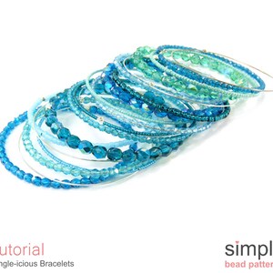 Pu&ograve; includere: Una pila di braccialetti di perline blu e turchese, ognuno con una base di filo d'argento. I braccialetti sono disposti in dimensioni graduate, con il pi&ugrave; grande in basso e il pi&ugrave; piccolo in alto. Tutti i braccialetti sono realizzati con piccole perline rotonde.