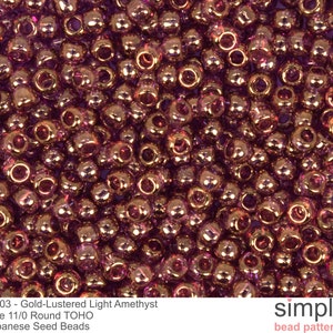 May include: Close-up of a pile of gold-lustered light amethyst Japanese seed beads. The beads are size 11/0 round TOHO. The image includes the text "#203 - Gold-Lustered Light Amethyst" and "simple bead patterns".
