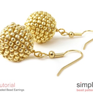 May include: A pair of gold beaded earrings with a spherical design. The earrings are made with small, round beads that are tightly packed together to create a smooth, rounded shape. The earrings are attached to gold hooks.