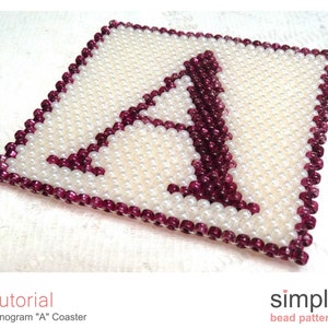 Puede incluir: Primer plano de un posavasos cuadrado de cuentas con la letra "A" en el centro. El posavasos está hecho con cuentas blancas y burdeos. El texto "Tutorial Monogram "A" Coaster" está debajo de la imagen.
