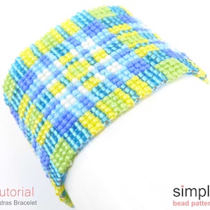 May include: A colorful beaded bracelet with a geometric pattern in shades of blue, green, yellow, and white. The bracelet is made with small seed beads and is woven in a traditional Madras style.