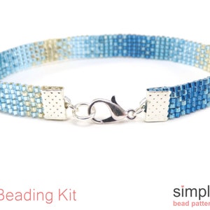May include: A beaded bracelet with a gradient of blue and tan colors. The bracelet is made of small, square beads and has a silver clasp. The words "Beading Kit" are in red text at the bottom of the image.