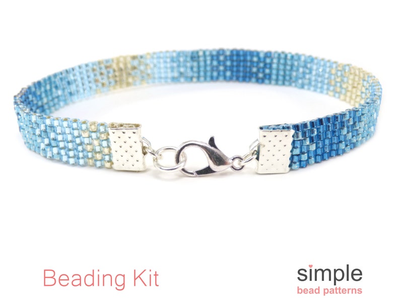 May include: A beaded bracelet with a gradient of blue and tan colors. The bracelet is made of small, square beads and has a silver clasp. The words "Beading Kit" are in red text at the bottom of the image.