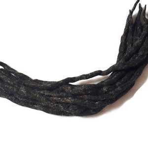 Könnte beinhalten: Ein Bündel schwarzer synthetischer Dreadlocks mit einem dezenten Schimmer.