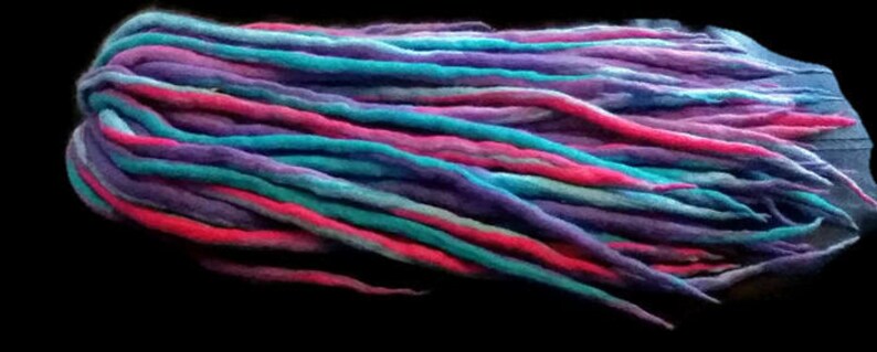 May include: A bundle of colorful wool dreadlocks in shades of pink, purple, blue, and teal.