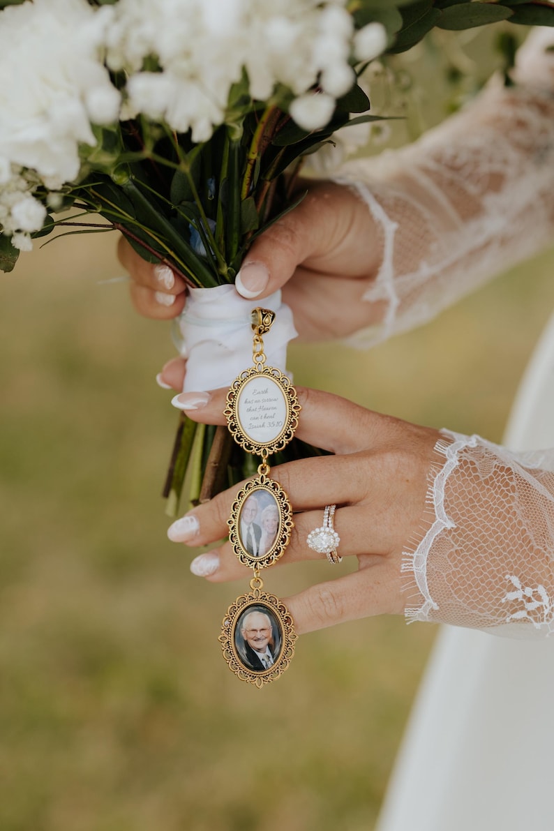 May include: A gold-toned metal pendant featuring three vertical oval frames with ornate filigree edges. The top frame contains white text on a light background, while the middle and bottom frames hold small portrait photographs of individuals.