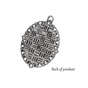 May include: The back of a silver pendant with a detailed, intricate design. The pendant has a loop at the top for attaching a chain.