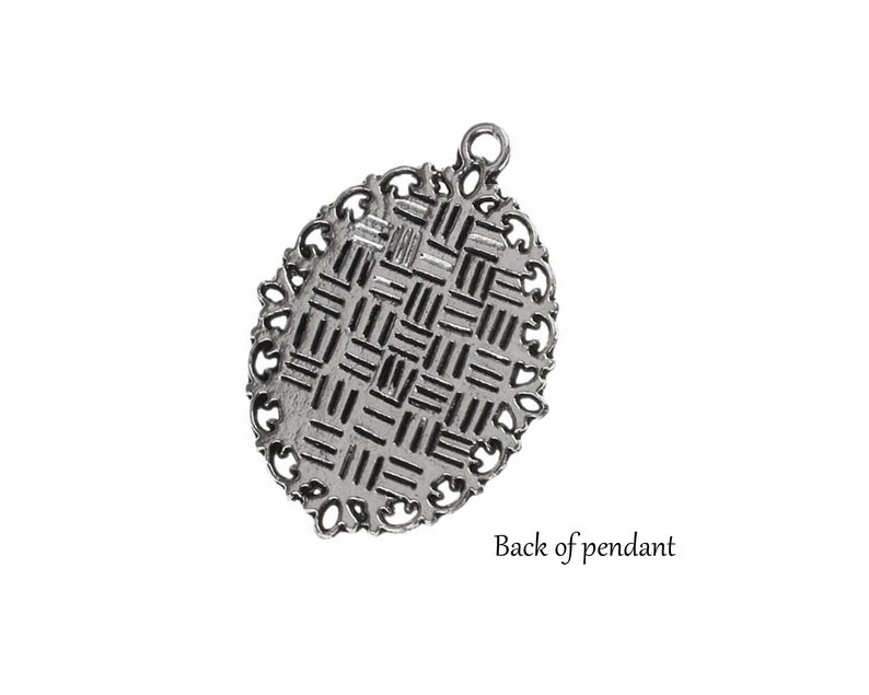 May include: The back of a silver pendant with a detailed, intricate design. The pendant has a loop at the top for attaching a chain.