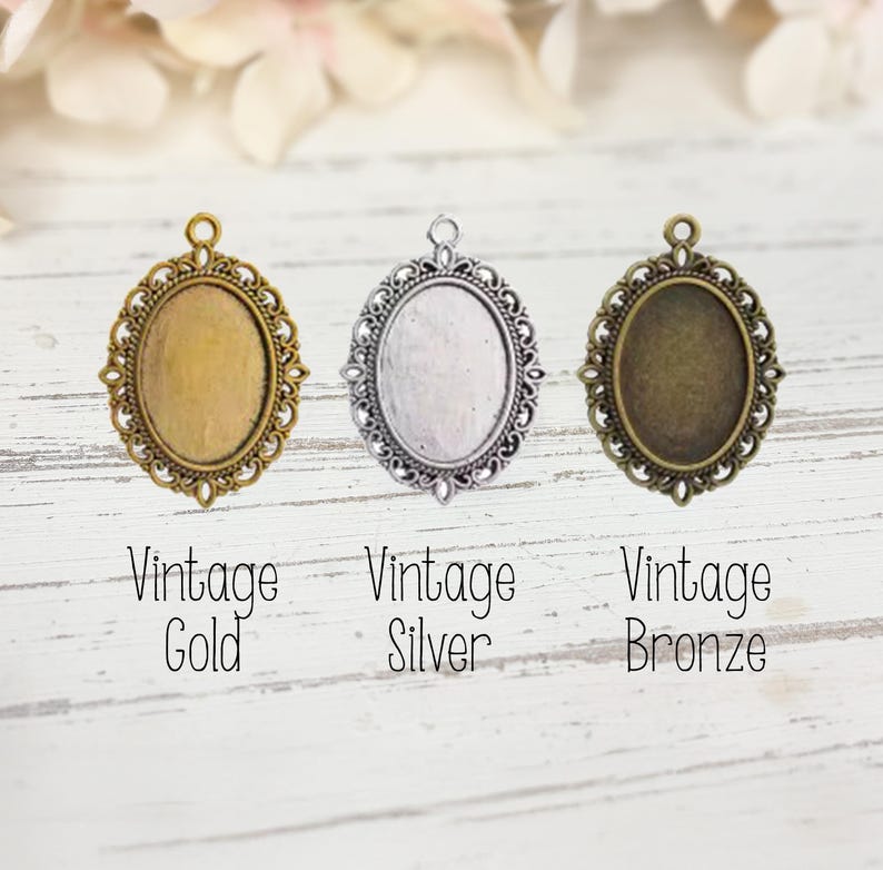 May include: Three oval pendant trays with ornate filigree borders in vintage gold, vintage silver, and vintage bronze finishes. Each metal frame features a small loop at the top for attachment. Text below reads: Vintage Gold, Vintage Silver, Vintage Bronze.