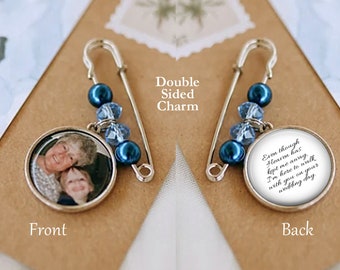 May include: A silver-toned safety pin brooch featuring a double-sided circular charm. One side displays a photograph of an older person and a child. The other side features the text: Even though Heaven has kept me away, I'm here to walk with you on your wedding day. The pin is accented with dark blue and light blue beads.