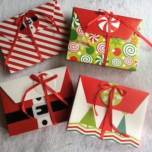May include: Four Christmas-themed gift envelopes. One has red and white stripes, another has a green and red pattern with candy cane accents, a third depicts a Santa suit, and the last has green trees and a zig-zag design.