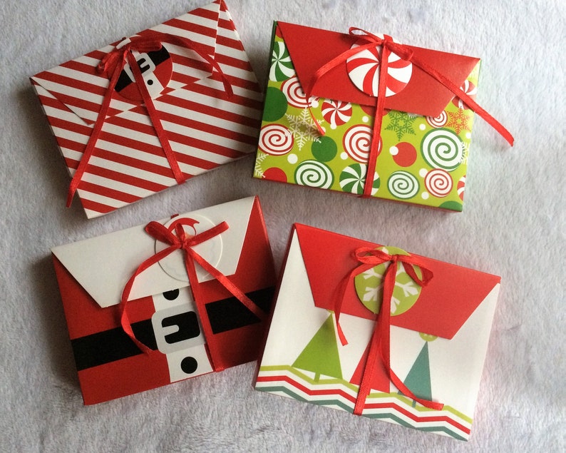 May include: Four Christmas-themed gift envelopes. One has red and white stripes, another has a green and red pattern with candy cane accents, a third depicts a Santa suit, and the last has green trees and a zig-zag design.