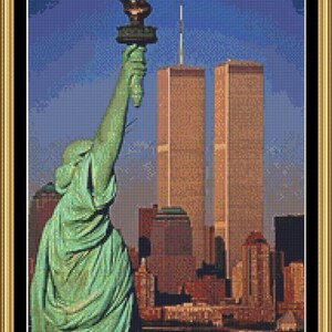 May include: A green statue of the Statue of Liberty stands in front of the Twin Towers in New York City. The sky is blue and the buildings are brown.