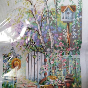 May include: Cross-stitch embroidery of a garden scene with a white picket fence, a blue birdhouse, a white gate with a heart, and a basket of flowers.