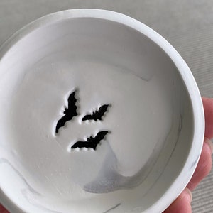 May include: White ceramic dish with a marbled design and three black bat silhouettes.