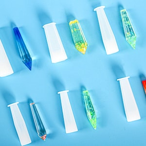 May include: Ten clear silicone molds shaped like pointed cones, with eight filled with colorful glitter-filled resin. The resin is in shades of blue, green, yellow, and orange.