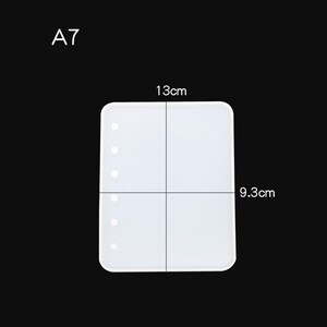 May include: White silicone mould for resin crafts, measuring 9.3 cm by 13 cm. The mould has a rectangular shape with rounded corners and eight evenly spaced holes along the left side.