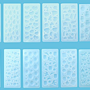 Peut inclure: Dix moules en silicone transparents pour la coulée de résine. Les moules présentent divers motifs, notamment des cœurs, des gouttes de pluie, des bonbons et des animaux.