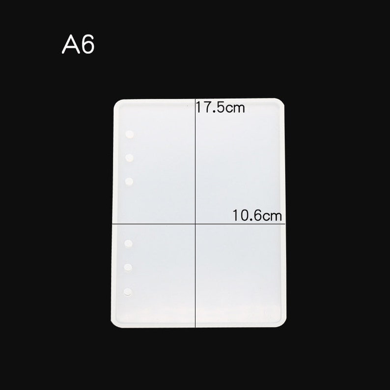 May include: A white silicone mould for resin crafts, shaped like a notebook with holes for binding. The mould measures 17.5 cm by 10.6 cm.