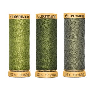 May include: Three spools of Gütermann thread in shades of green. The spools have a wooden base and a gold-coloured top with the Gütermann logo. Each spool contains 100 metres or 110 yards of thread.