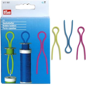 May include: A pack of four Prym bobbin holders in green, blue, pink and yellow. The bobbin holders are made of flexible plastic and are designed to hold spools of thread.